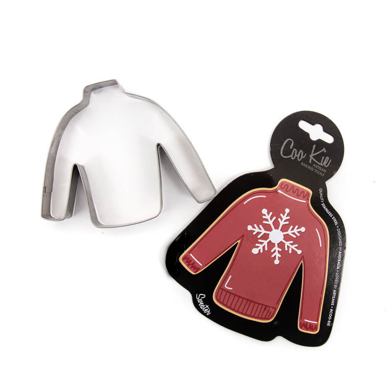 Image of jumper cookie cutter separated from its black cardboard backing depicting a red jumper with a snowflake on it. Shown against a white backdrop. 