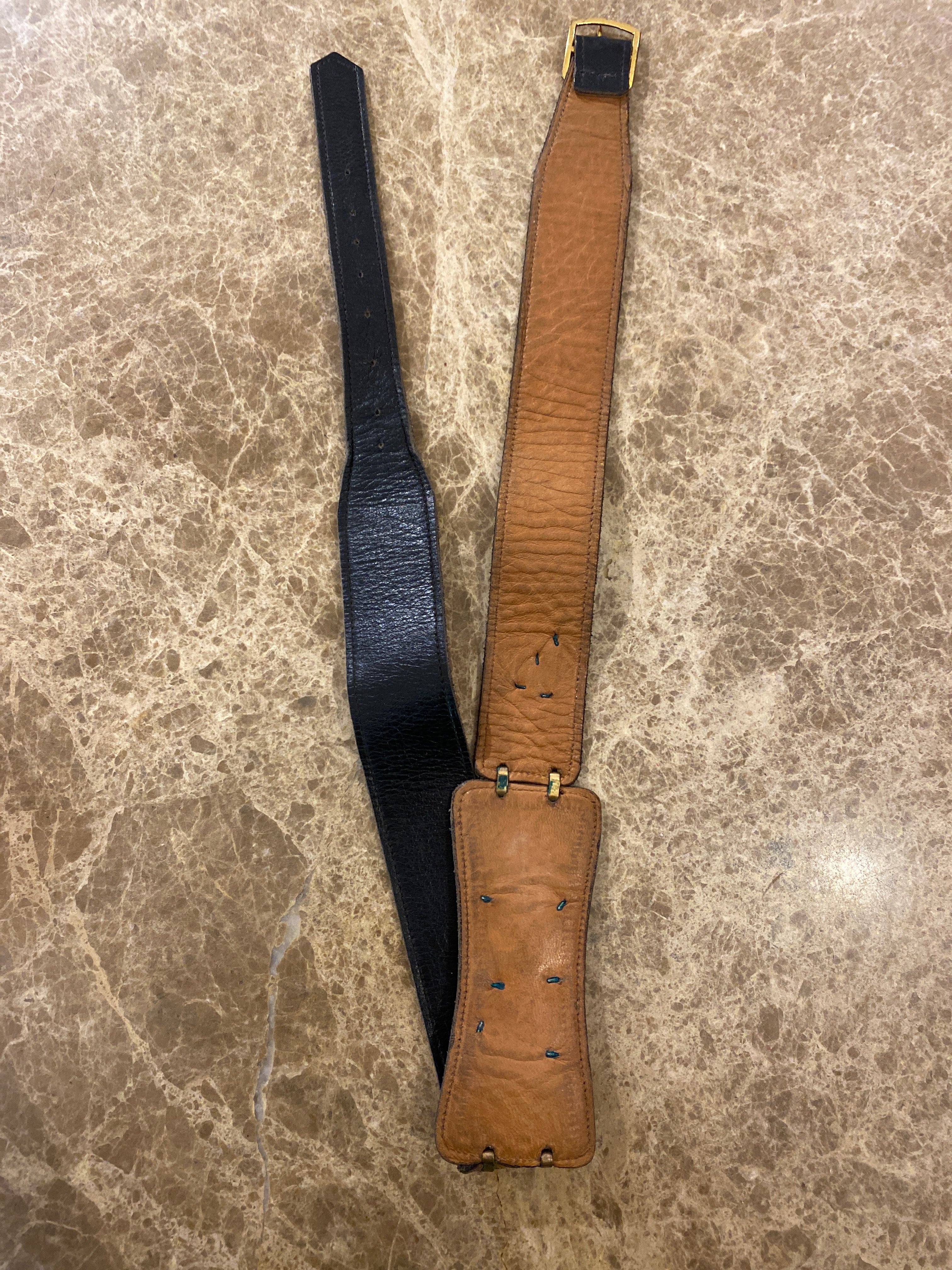 Vintage dark brown leather belt that is designed to buckle at a persons back, with three beautiful enamel embellishments attached to the belt; a crouched skier, a snow covered mountain chalet with two trees and a group of three skiers relaxing. 2