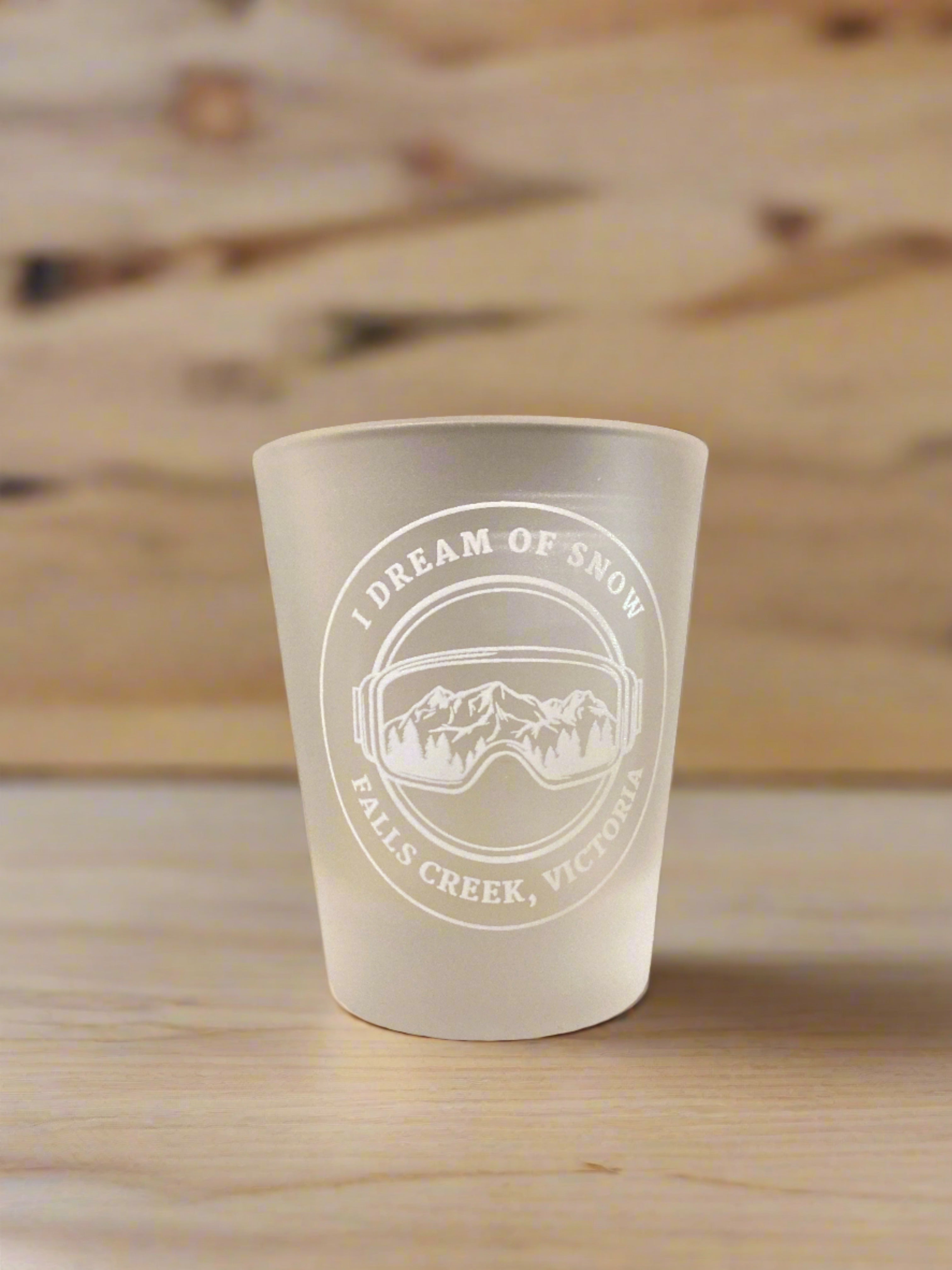 Clear Glass Shot Glass with white I Dream Of Snow Falls Creek Victoria printing including and image of goggles and a mountain.