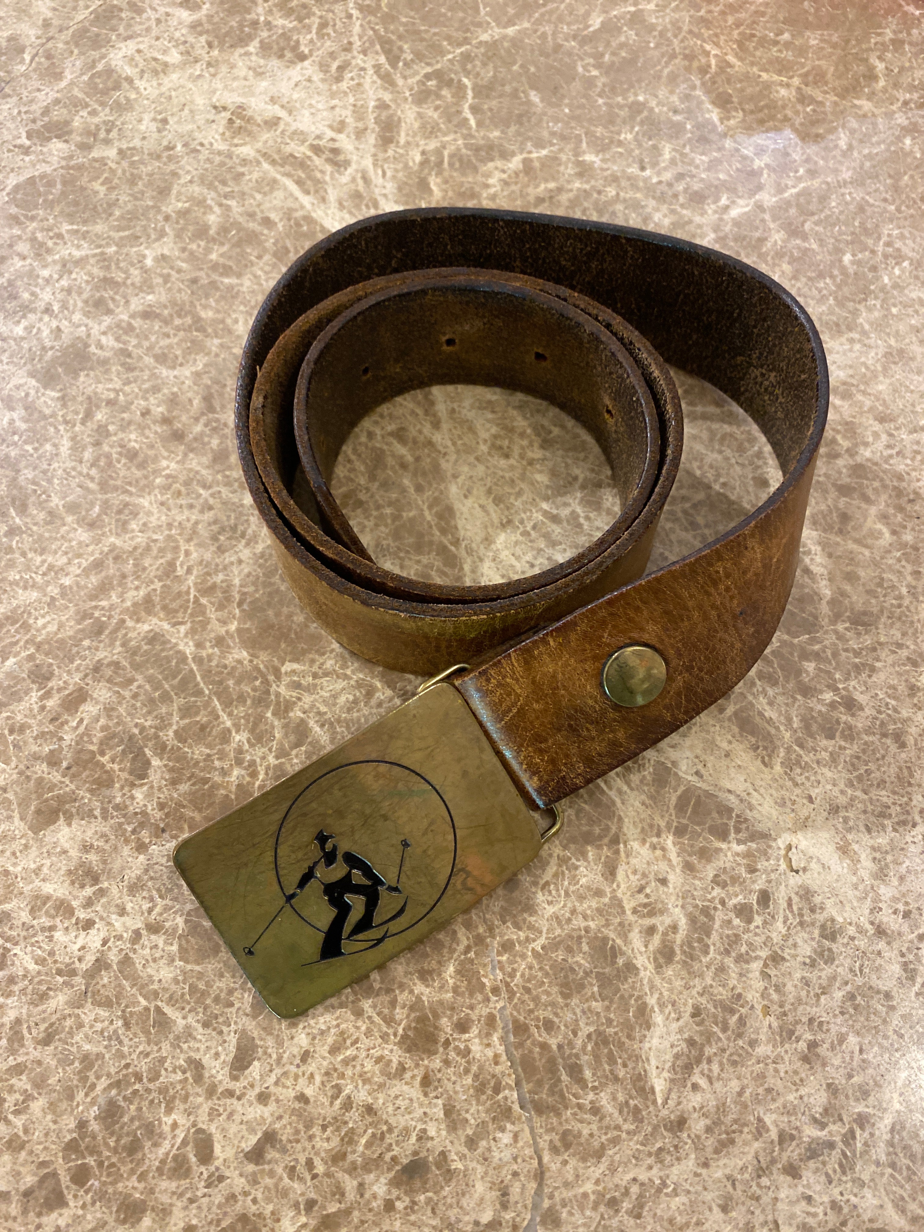 Vintage leather belt with an Ampersand Brass skier buckle.  shown on a brown & cream Ceasarstone bench