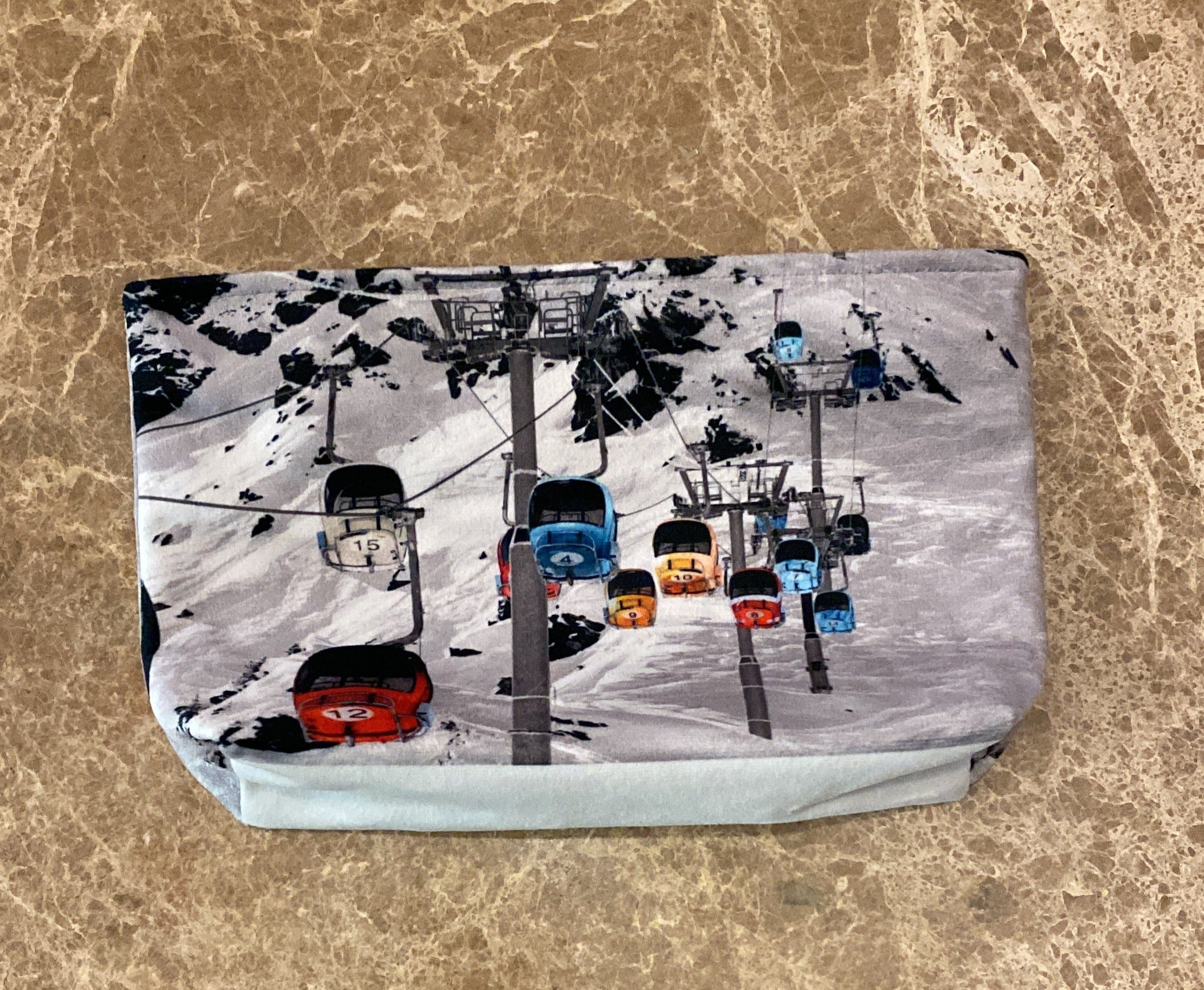 Photo of coloured gondola against the backdrop of a ski slope resting on a marble table