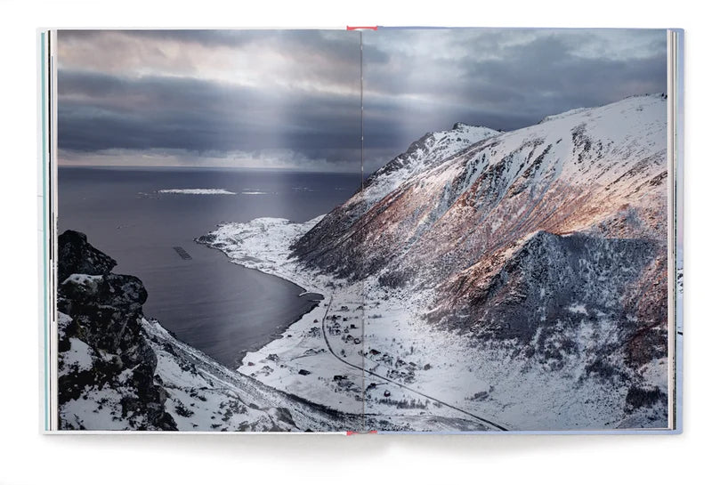 Image shows a page of the book, a photograph of a mountainous landscape under grey sky, falling away to a road at it's base before the land meets a calm sea