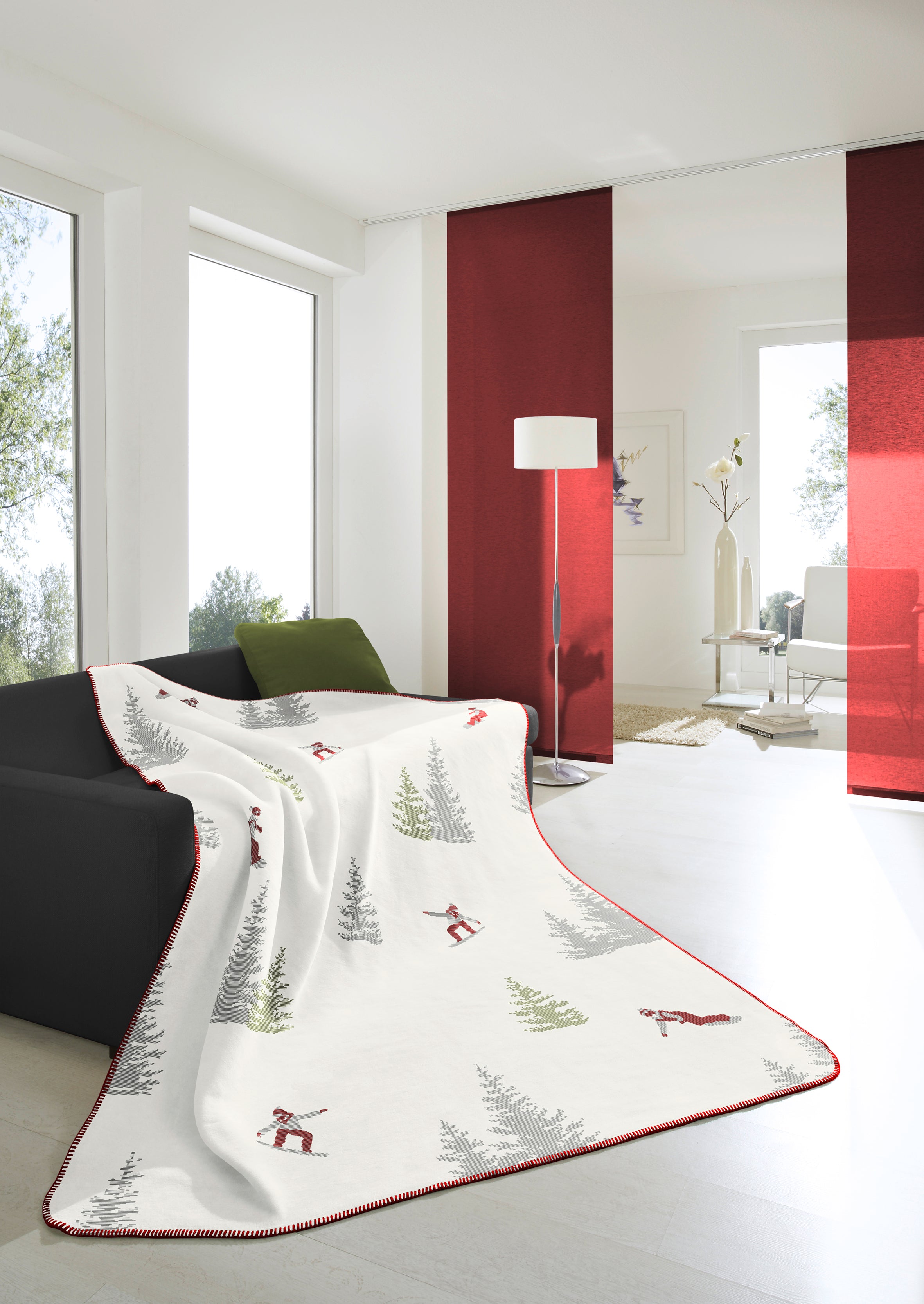 Snowboard Blanket, draped over a grey couch  with a green cushion in a white & red lounge room