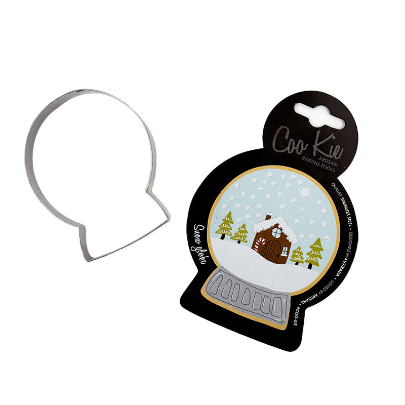 Image of snow globe cookie cutter separated from its black cardboard backing depicting a snow globe with a with snowy cabin scene within it. Shown against a white backdrop. 