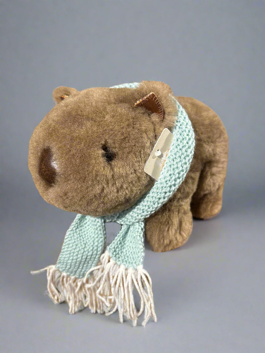 Winnie the Sheepskin Wombat toy, shown with teal blue dolls scarf. Winnies ears, nose and claws are leather. Side view. Winnie the Wombat sold separately.