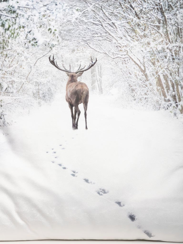 Snowy Landscape with Deer Cushion, against a pale wall.