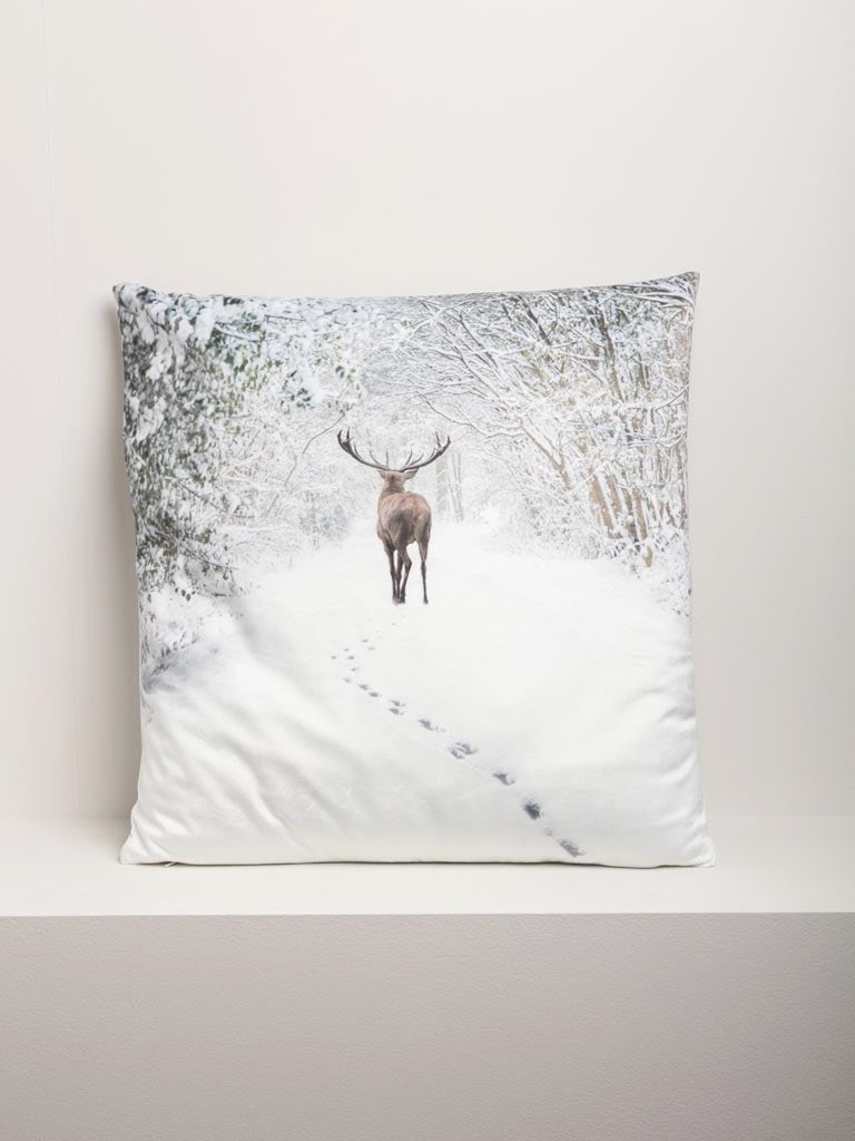 Snowy Landscape with Deer Cushion, on a pale ledge against a pale wall.