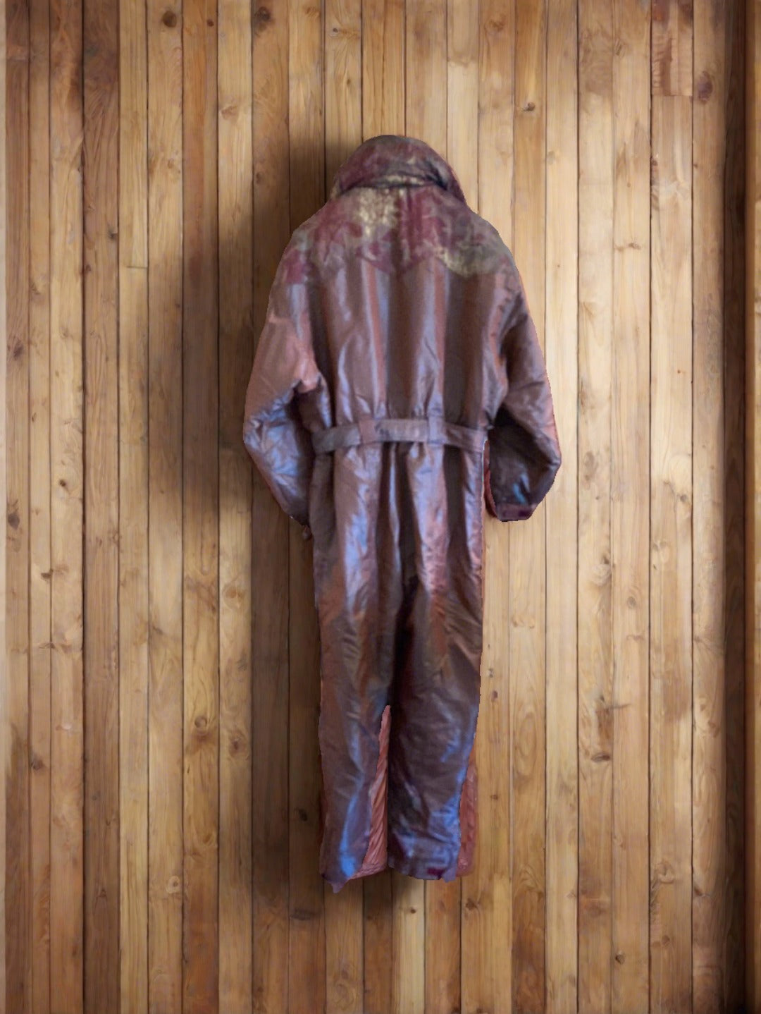 Vintage Tresspass shimmery Brown, Maroon & Gold One Piece Ski Suit. Rear view. Against a wood wall