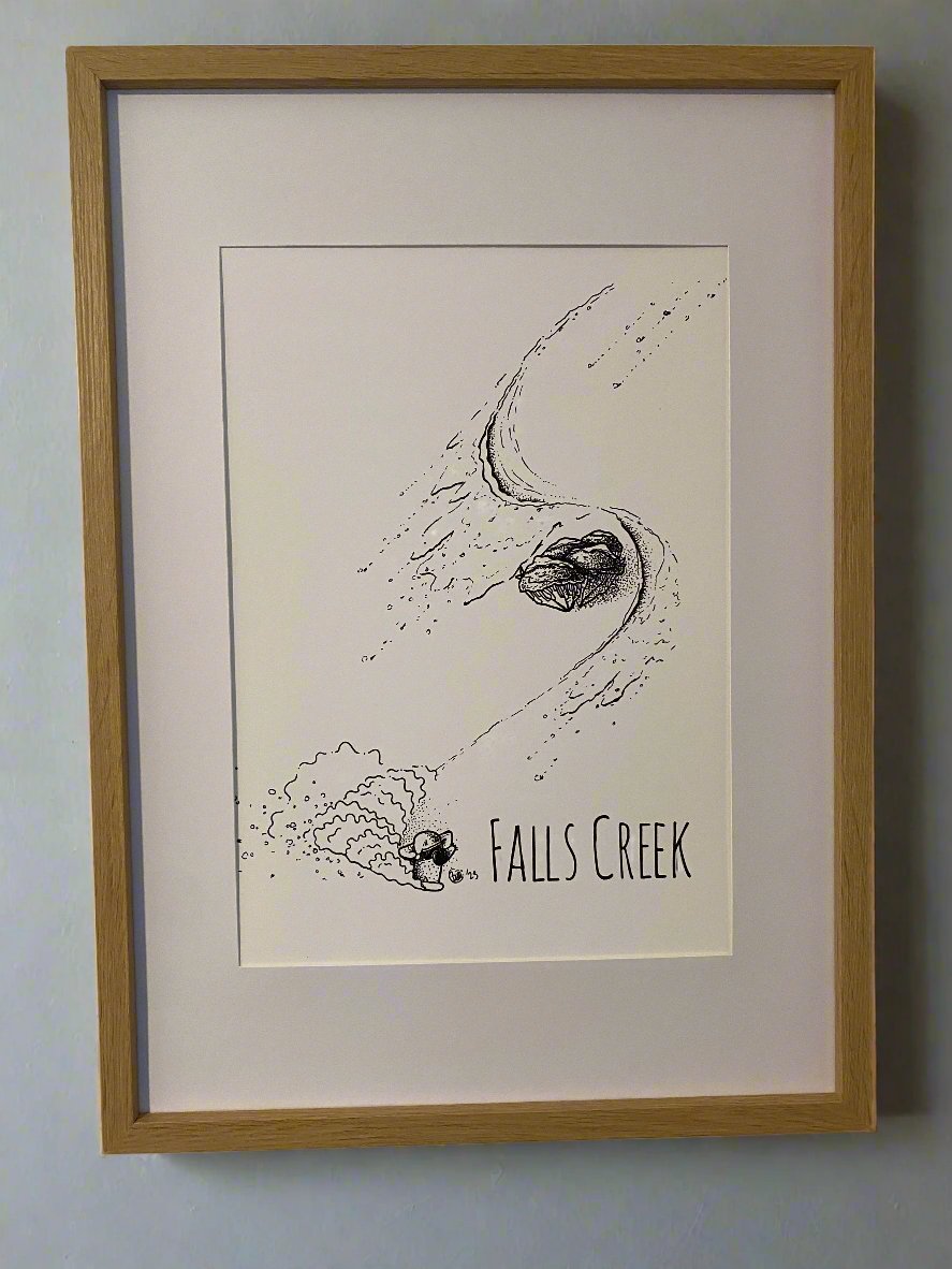 Print of a snowboarding koala turning around snow gum trees, with the words Falls Creek printed underneath the image, shown in a beechwood frame, close up.