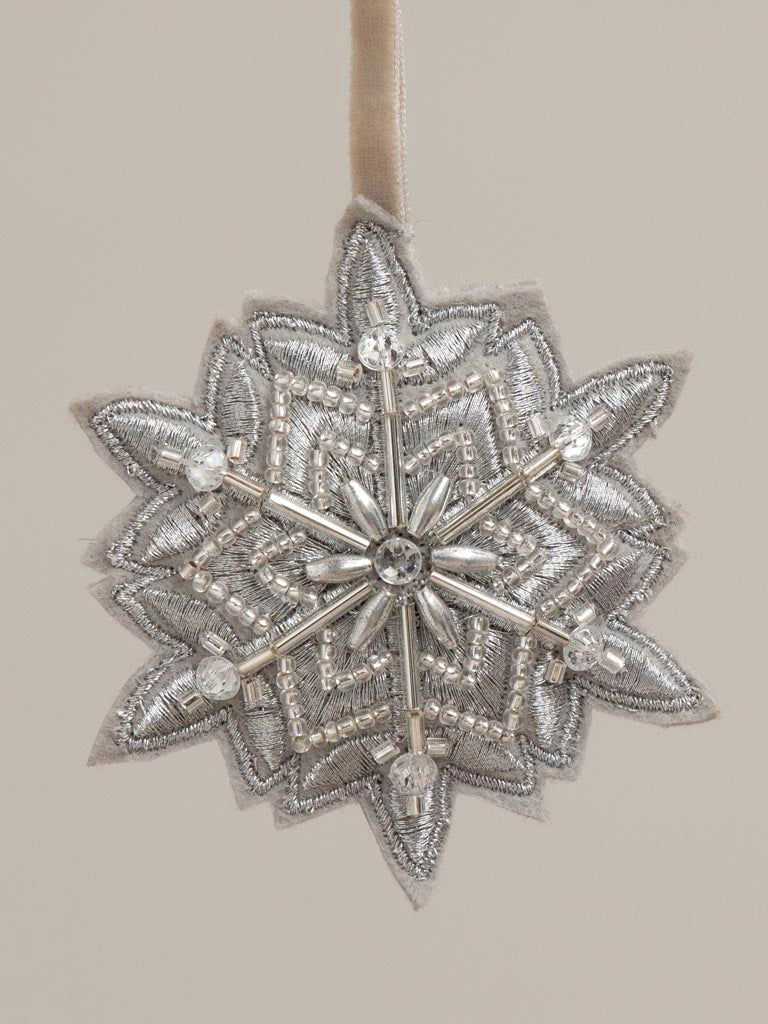 Hanging silver beaded snowflake 8cm, hanging from a branch. Close up image