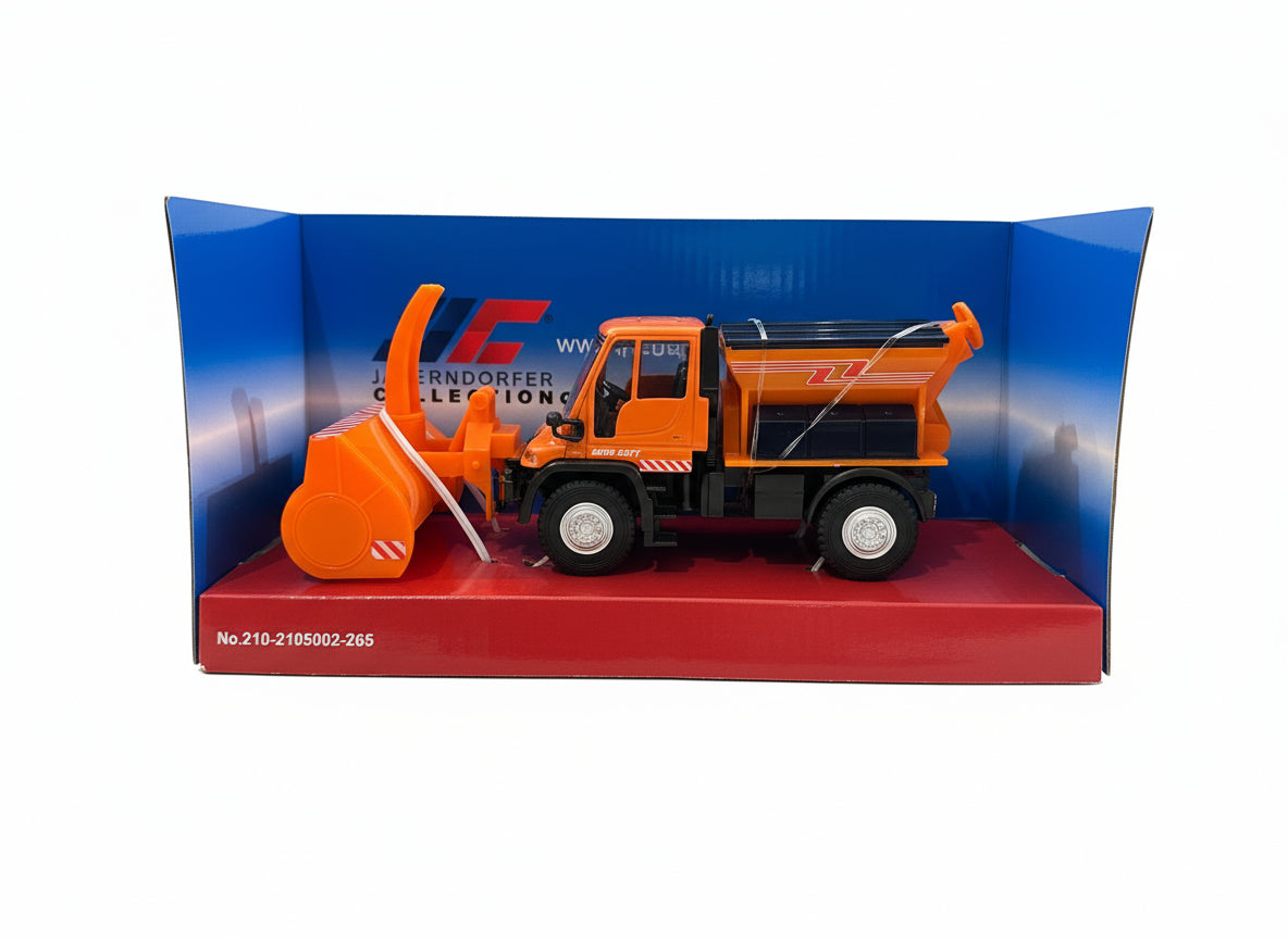 This image shows the Jaegerndorfer Snow Clearing Truck with snow blower attachment from the side, in part of it's blue and red box on a white background. 
