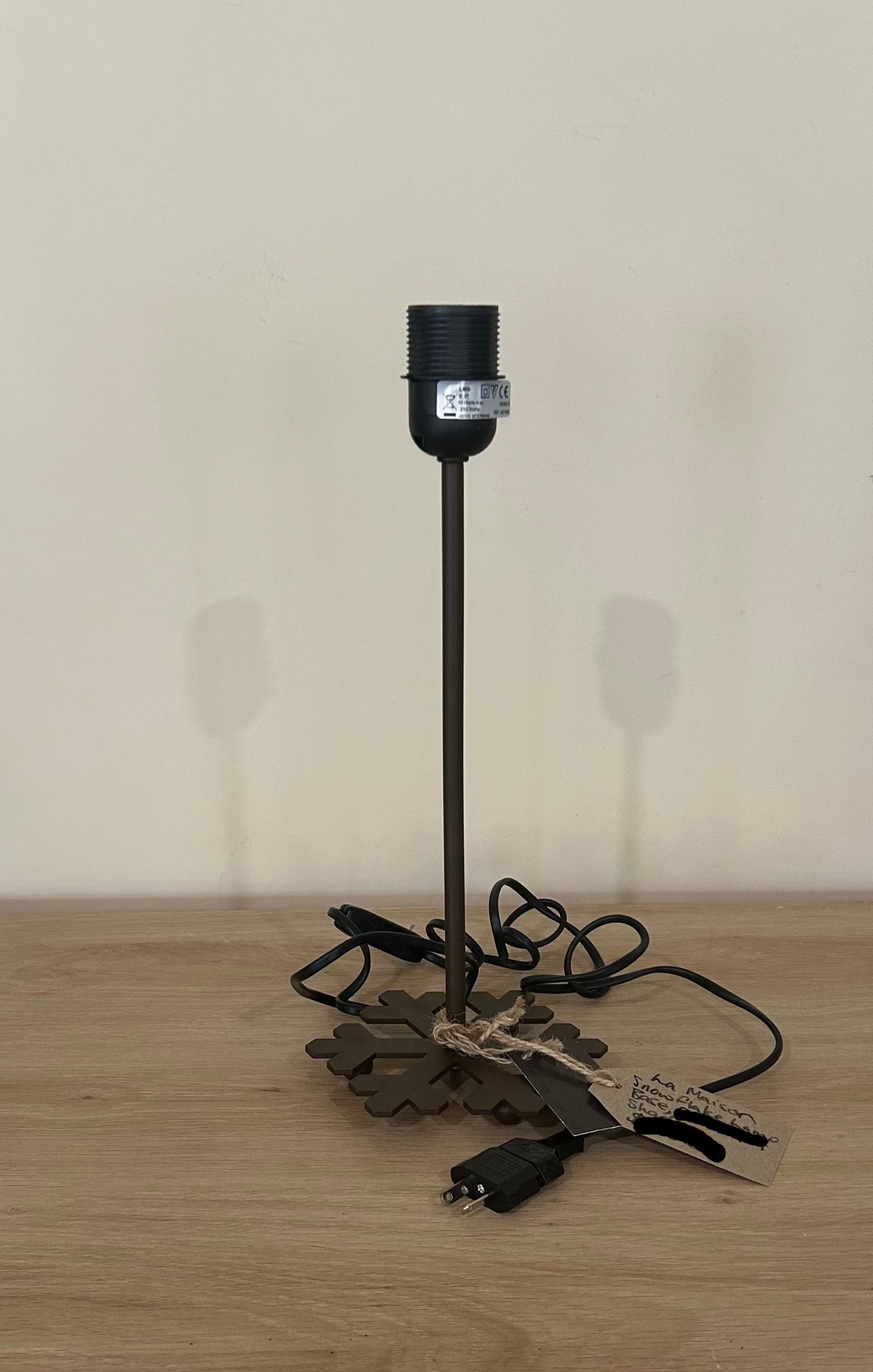 La Maison De Gaspard Snowflake metal lamp with the snowflake forming the base of the lamp. On wooden table top