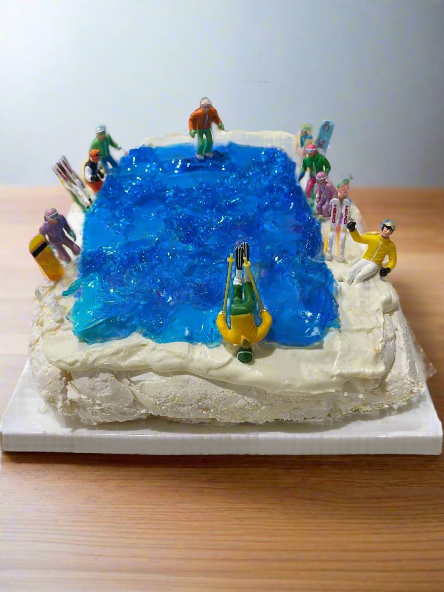 Sitting and standing skiers & snowboarders on a "pond skim' Pavlova dessert. front on view