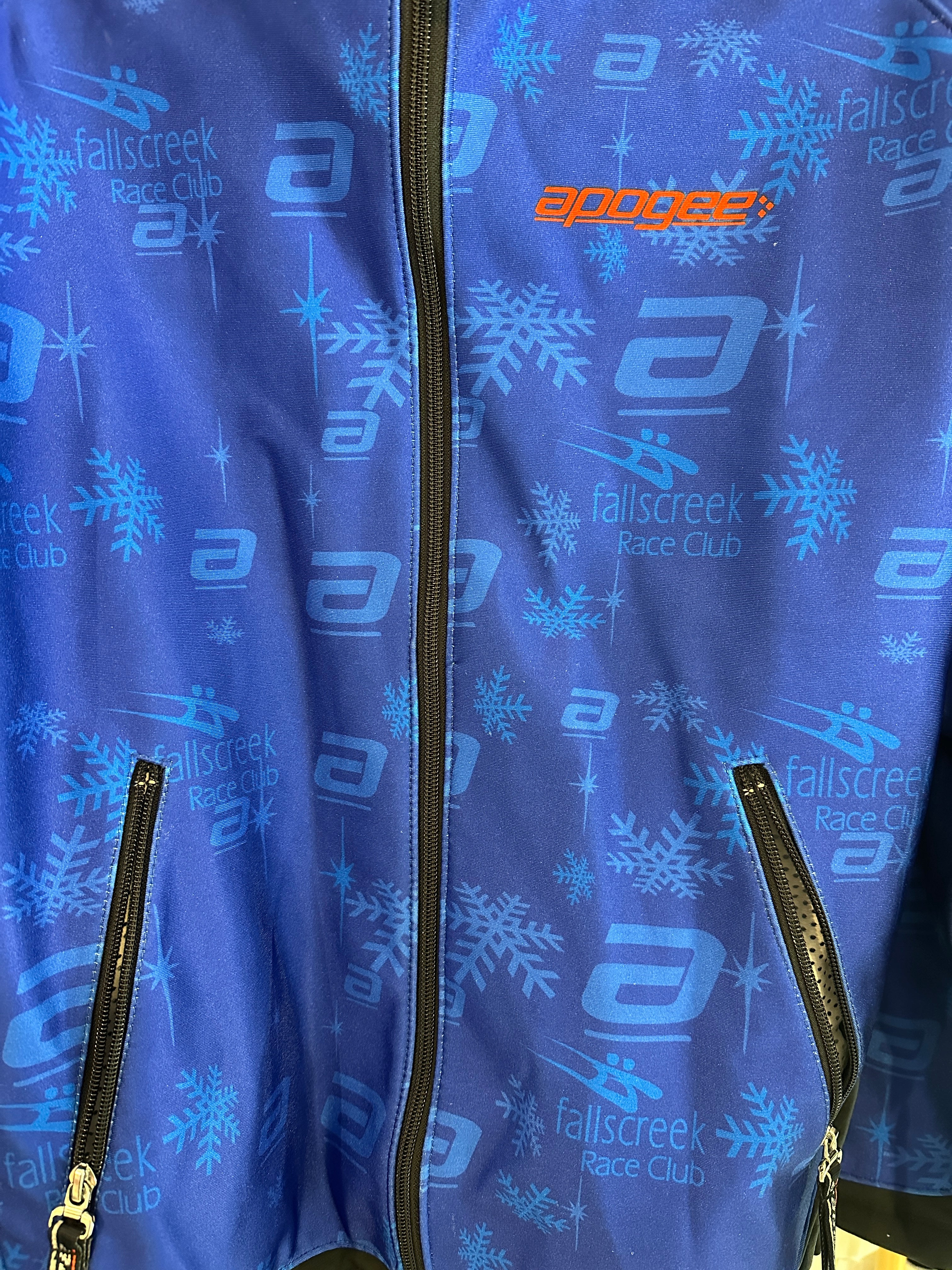 Early 2000's Fall Creek Race Club Padded Race Shell. Close up of print on fabric featuring the words 'falls creek race club' and the 'swish' logo in navy and light blue.