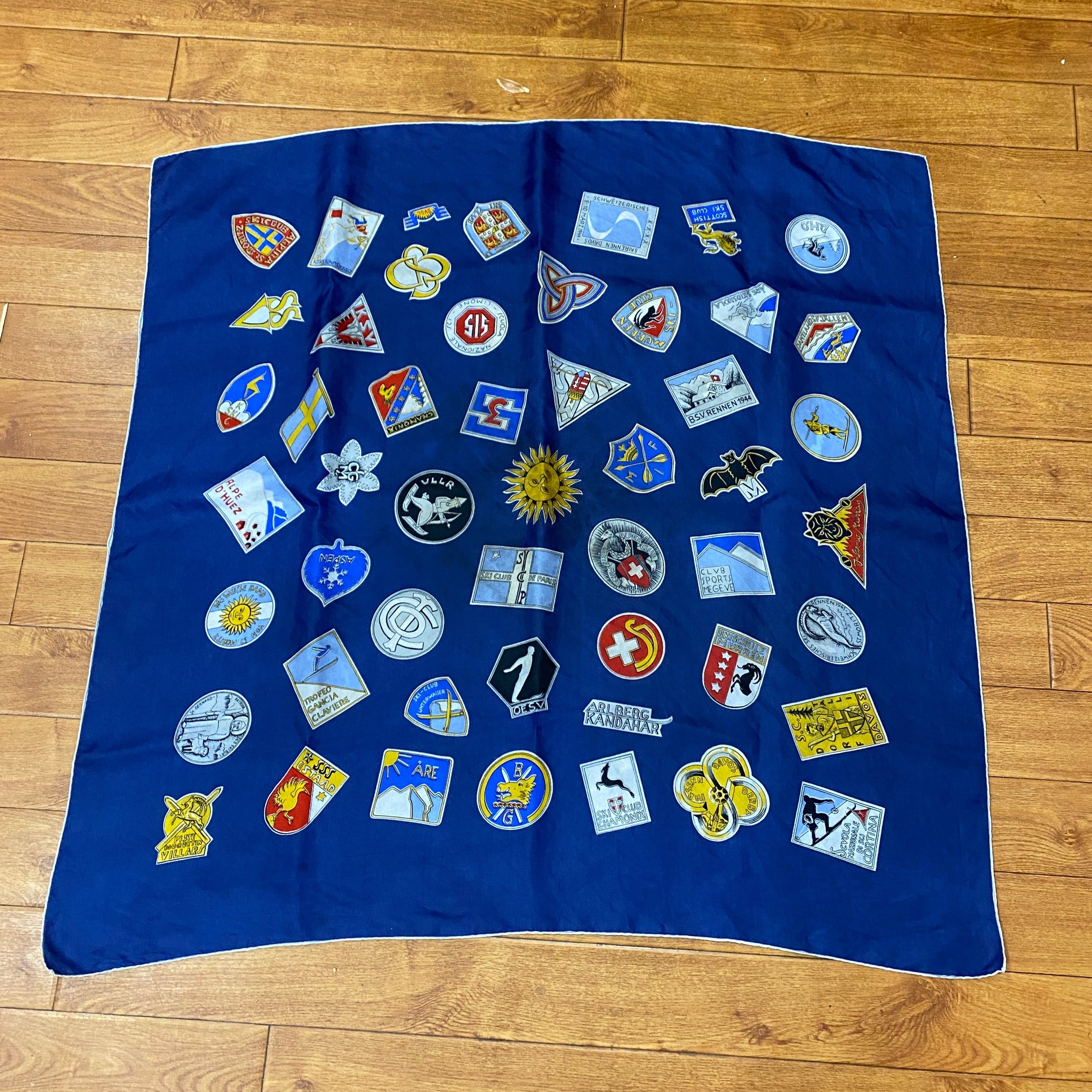 Vintage Souvenir Ski Patch Scarf in Blue. against wooden background.