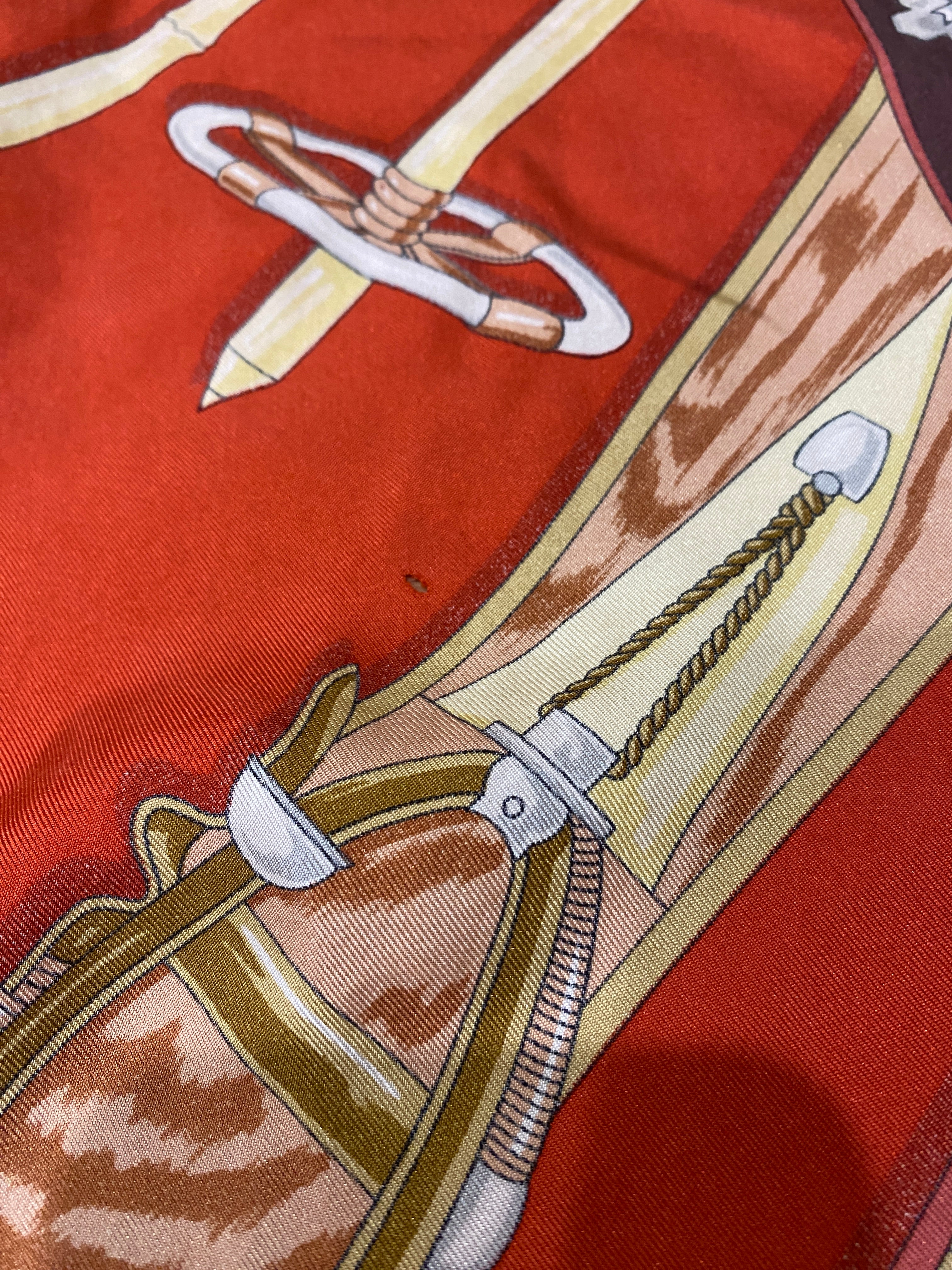 Bogner Silk Vintage Ski Scarf in red, brown white and beige. Snowflakes border the scarf, with the central square illustrating wooden skis and poles. Close up shows small hole in scarf.