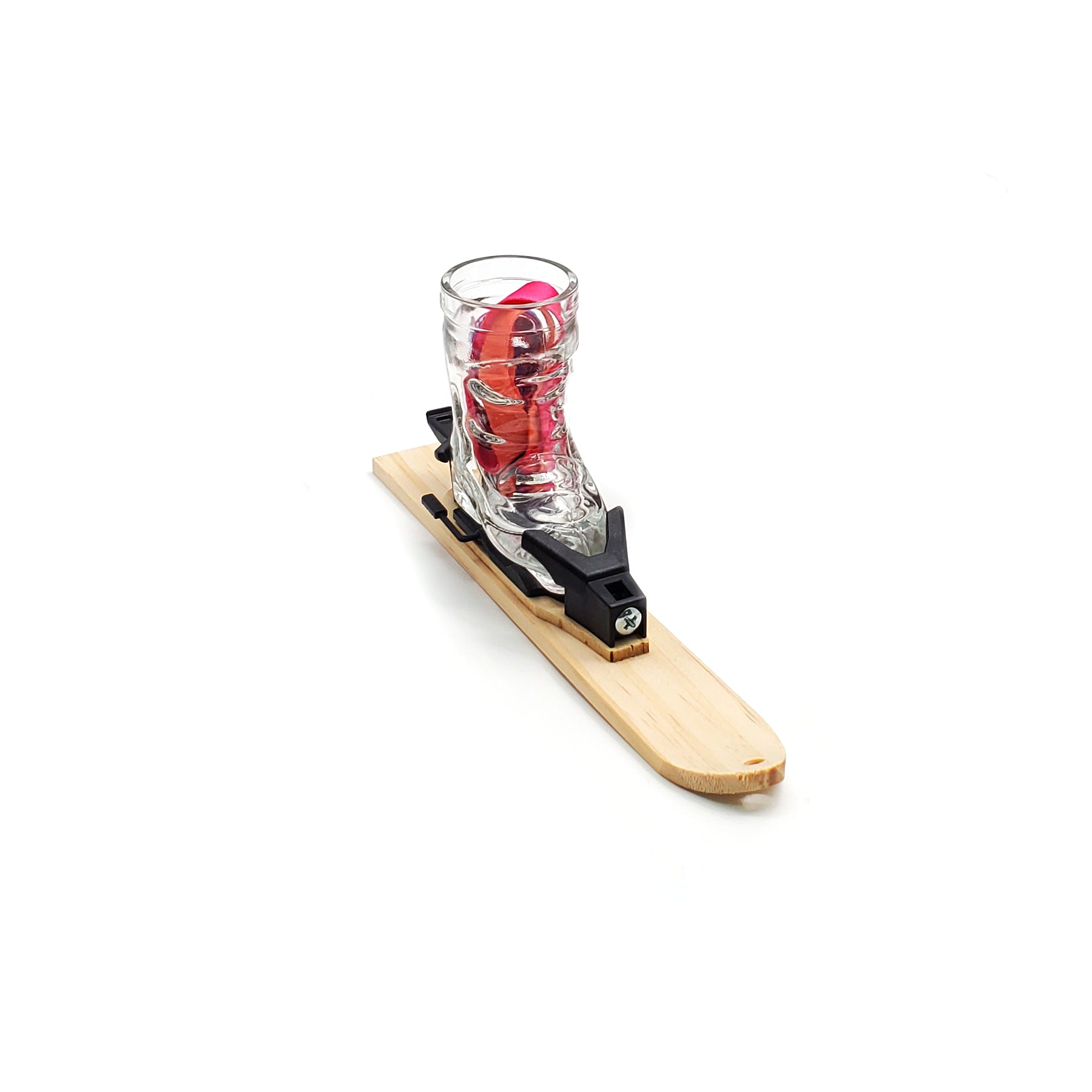 Photo of a wooden tray in the shape of small ski. The ski tray has a hole drilled into the tip of the ski and a small raised mounting platform for the Apr√®s Allstar boot shot glass and bindings.  A red lanyard is sitting inside the glass Image is set against a white backdrop