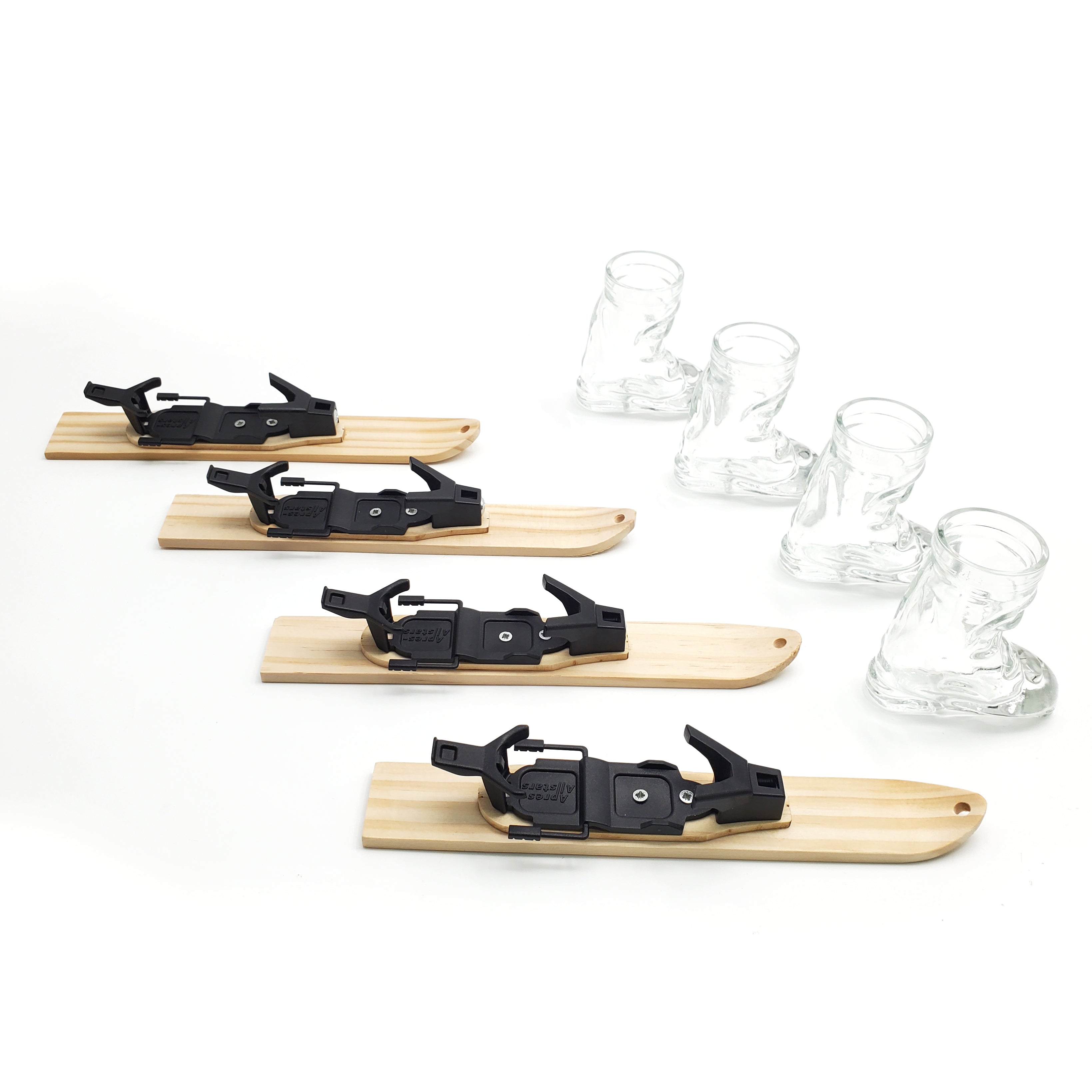 Photo of 4 wooden trays in the shape of small skis. Each ski tray has a hole drilled into the tip of the ski and a small raised mounting platform for the Apr√®s Allstar boot shot glass and bindings. Image is set against a white backdrop