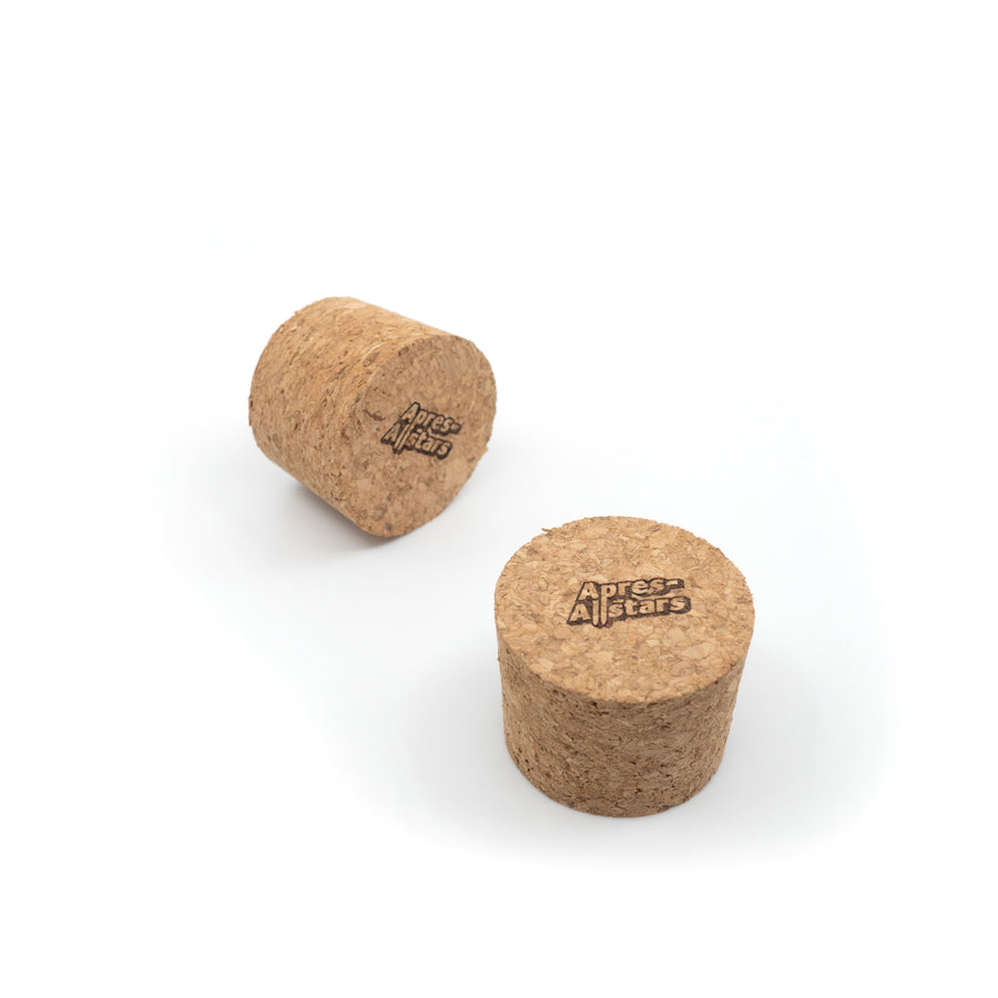 Photo of a pair of Apres Allstar shot glass corks, branded on top with the words Apres Allstar. Image is set against a white backdrop.