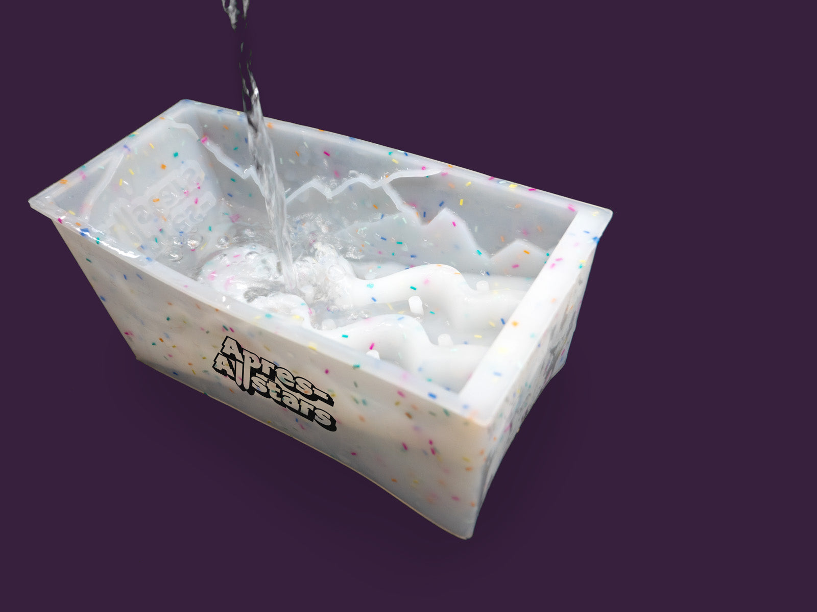 Photo of a white speckled plastic mould that water is being poured into. The image is set against a purple backdrop.