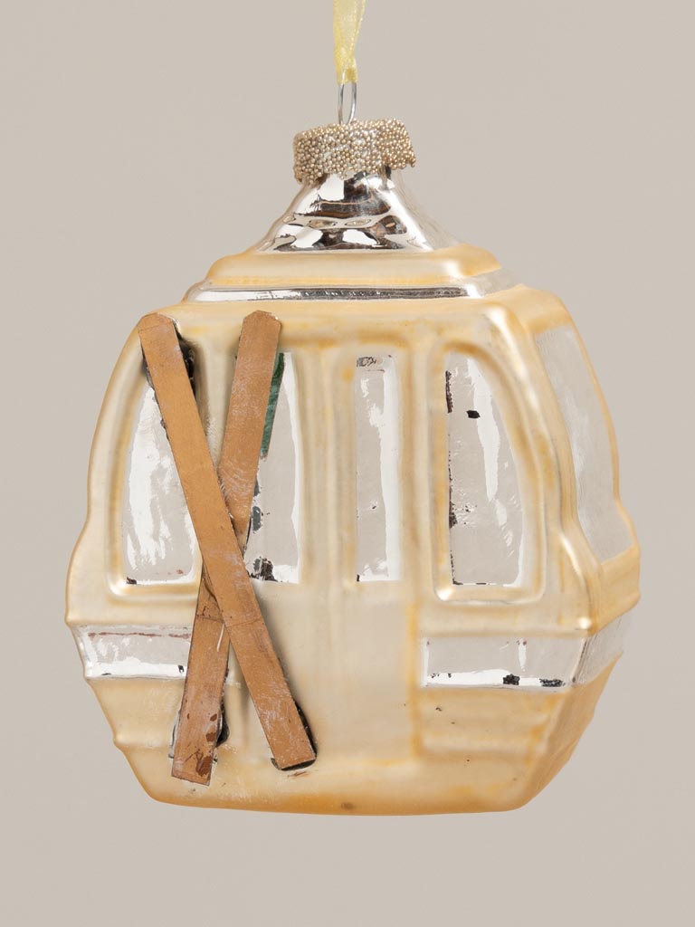 Gold gondola hanging from a branch against a pale background