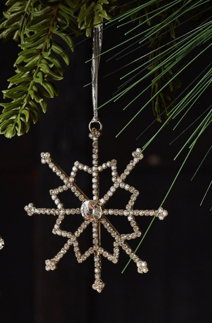 Jewel Snowflake steel and glass hanging ornament hanging from Christmas tree branches against a dark background