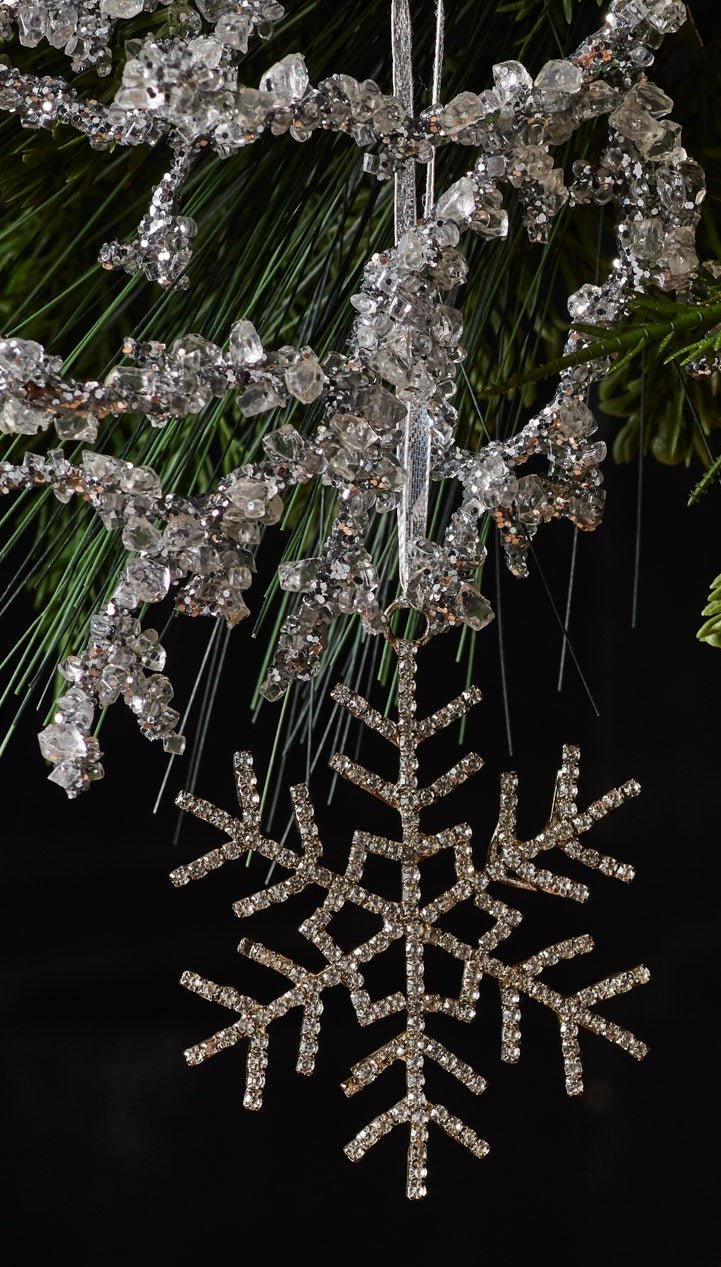 1 Jewel Snowflake steel and glass hanging ornaments hanging from Christmas tree branches against a dark background