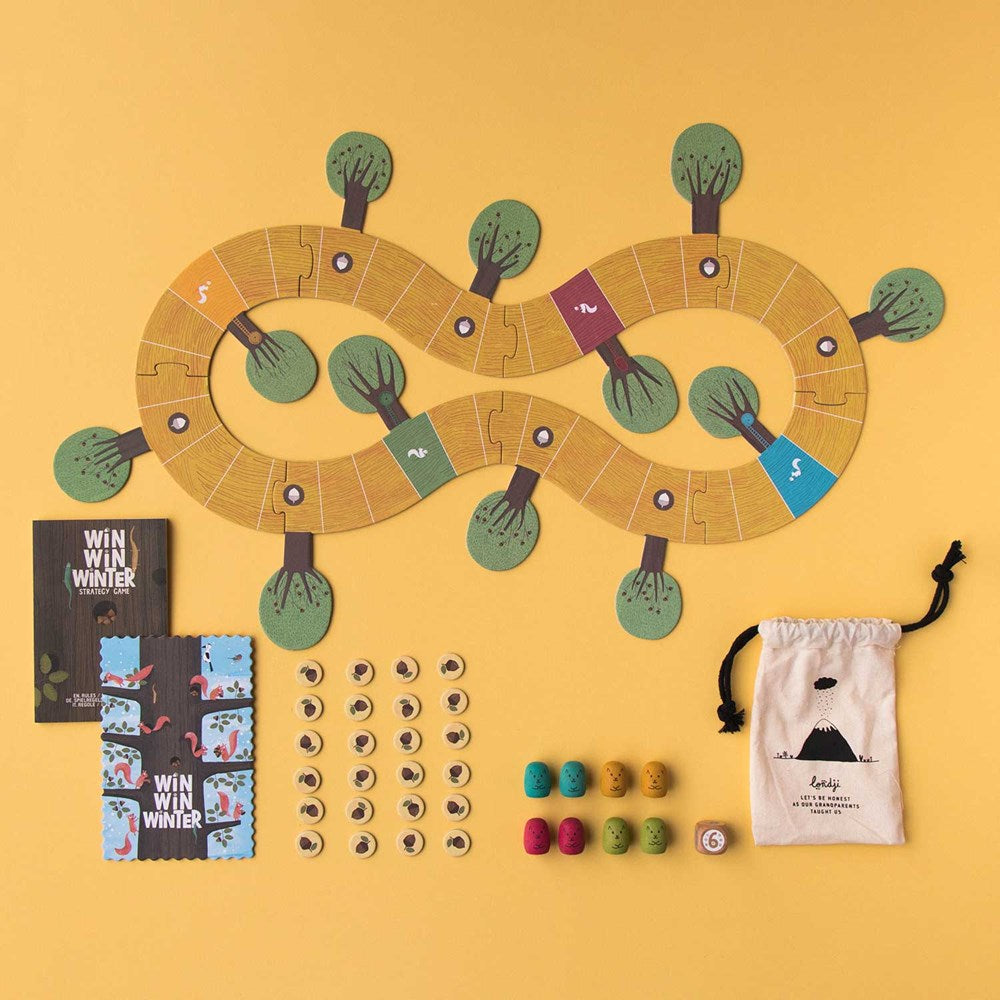 Image shows an overhead view of the unpacked Win Win Winter game; game board, game pieces, printed cards and a canvas draw string bag. Shown against a yellow backdrop.