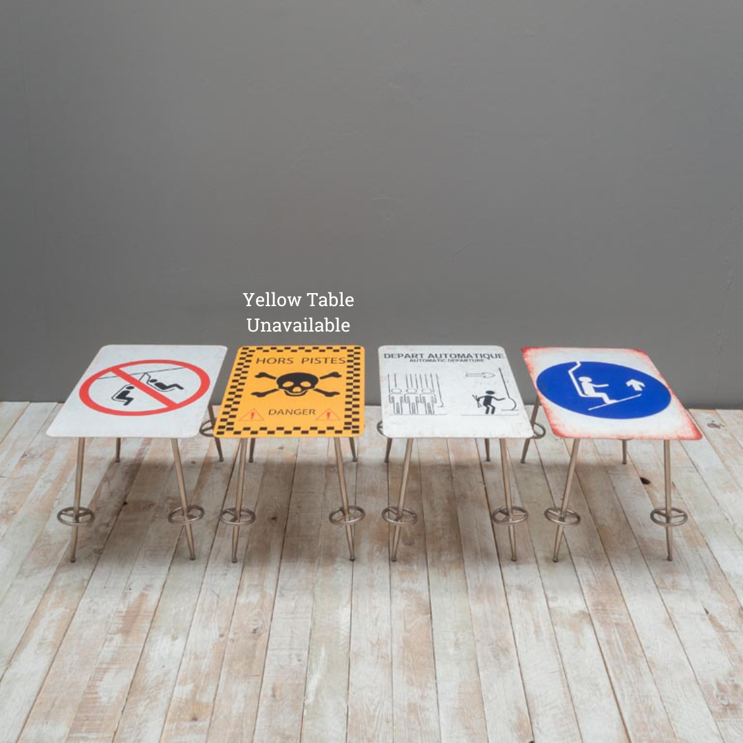 Small 'no swinging the chair', 'Chair Lift' & "Automatic Start' side tables, each with four legs shaped as ski poles, on wooden floor against a grey wall