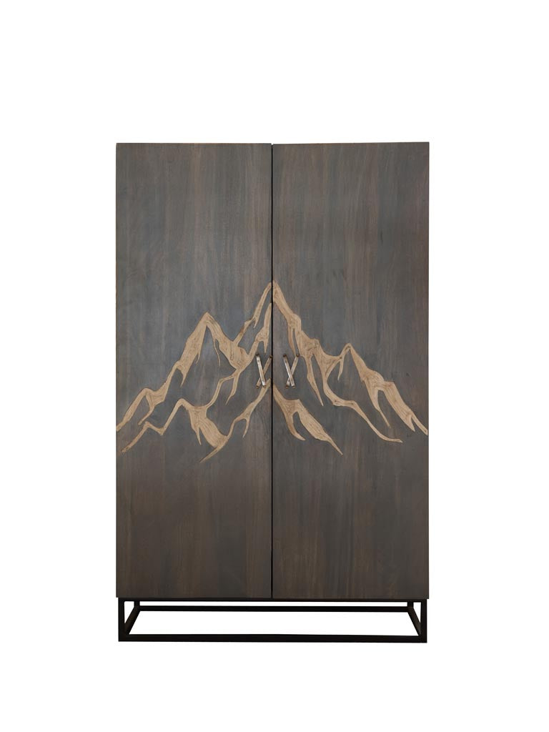 Wooden Cabinet engraved with a mountain & brass ski shaped handles with square metal base & legs on a white panel background