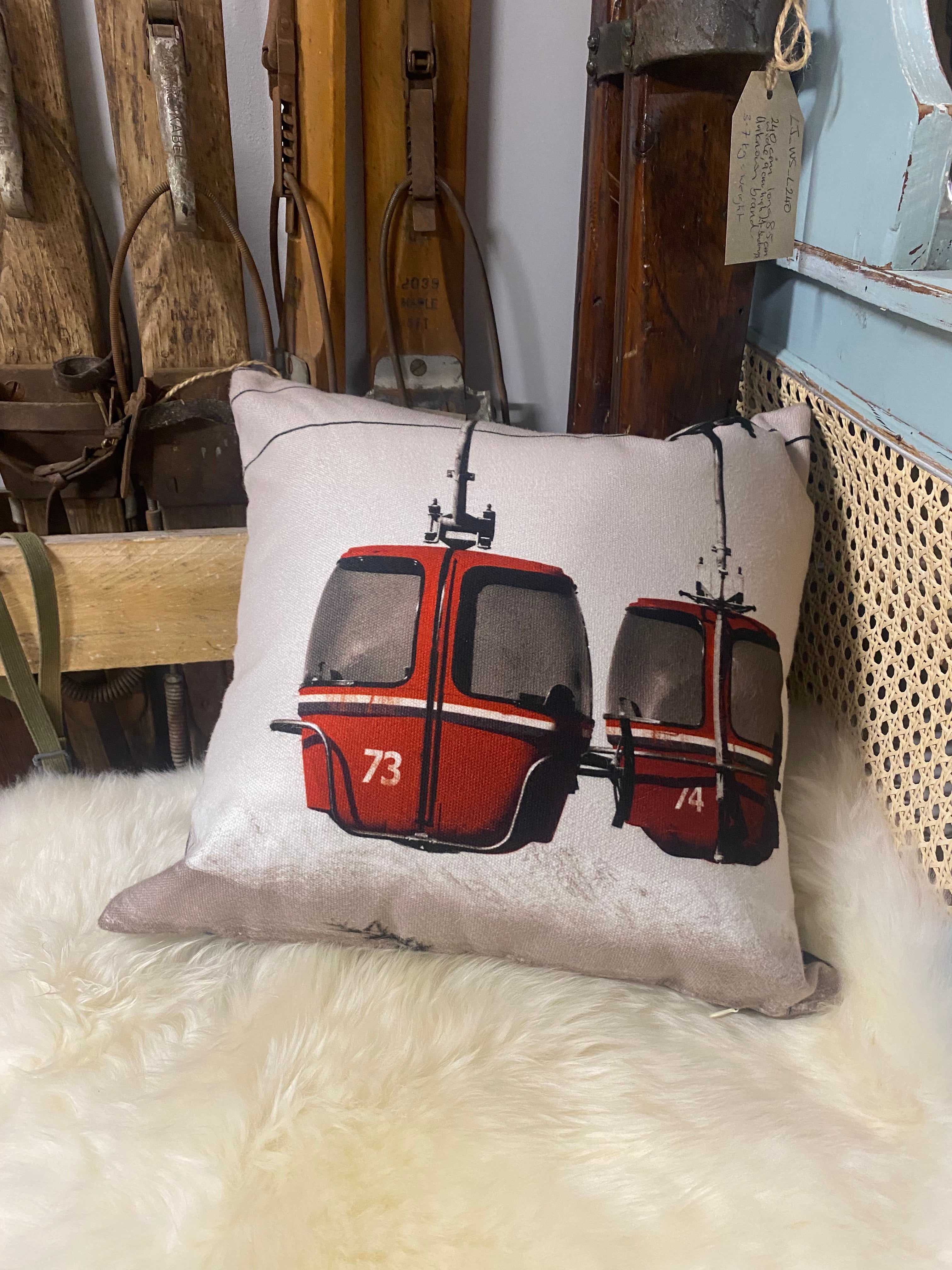  Cushion with vintage photo of red egg gondolas against a white mountain sky
