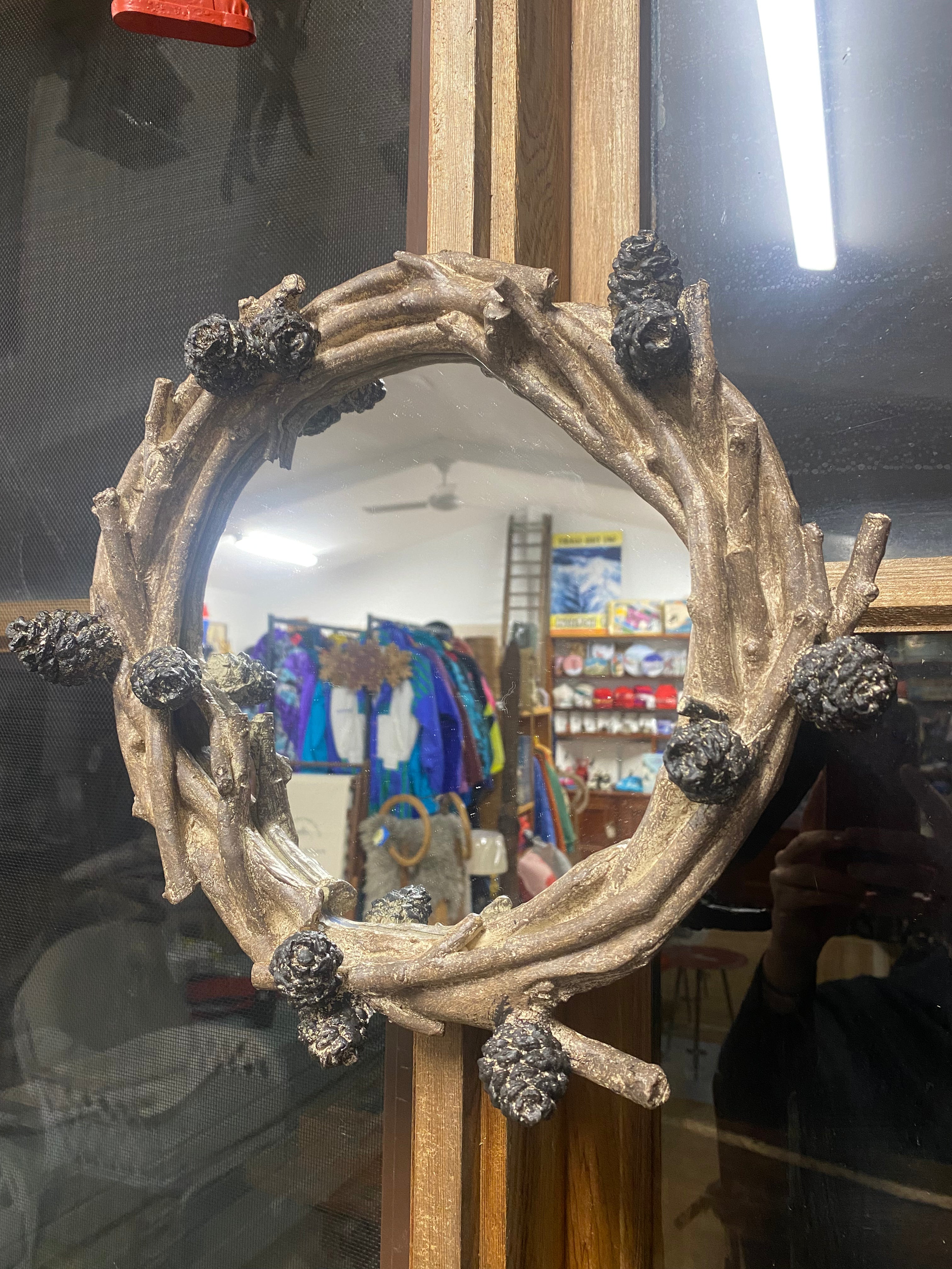 Pinecone mirror: Mirror framed by resin branches and pinecones, hanging on a window frame reflecting the I Dream of Snow Store