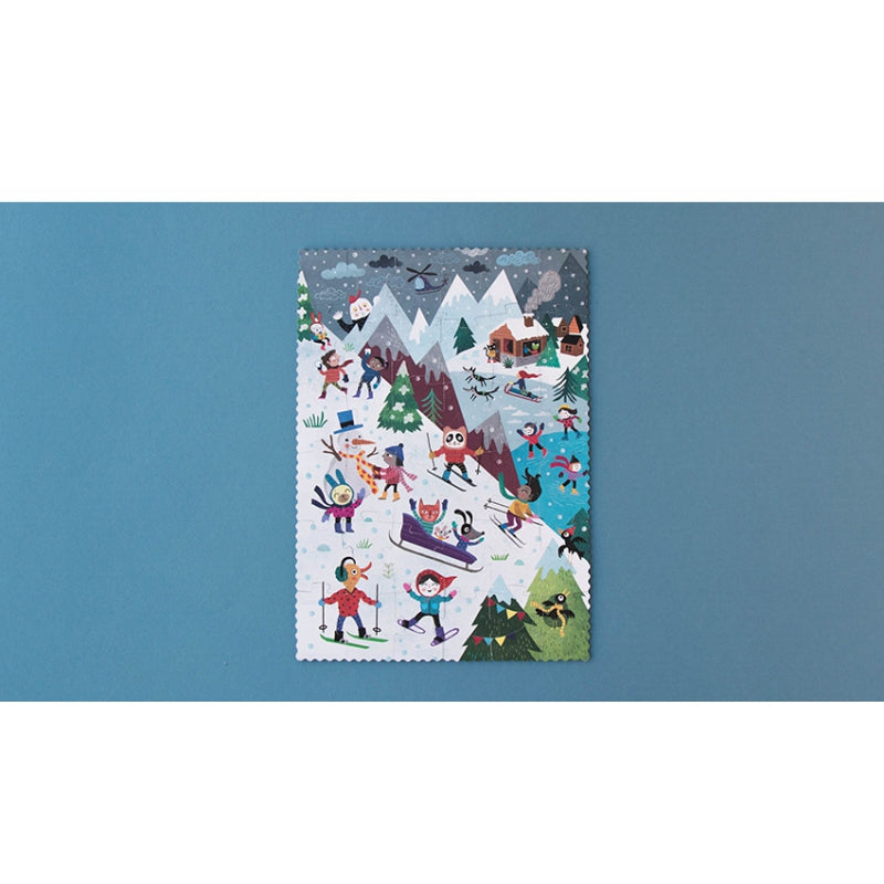 Image shows the completed puzzle with images of people and animals enjoying winter snow activities, against a blue background with a white border