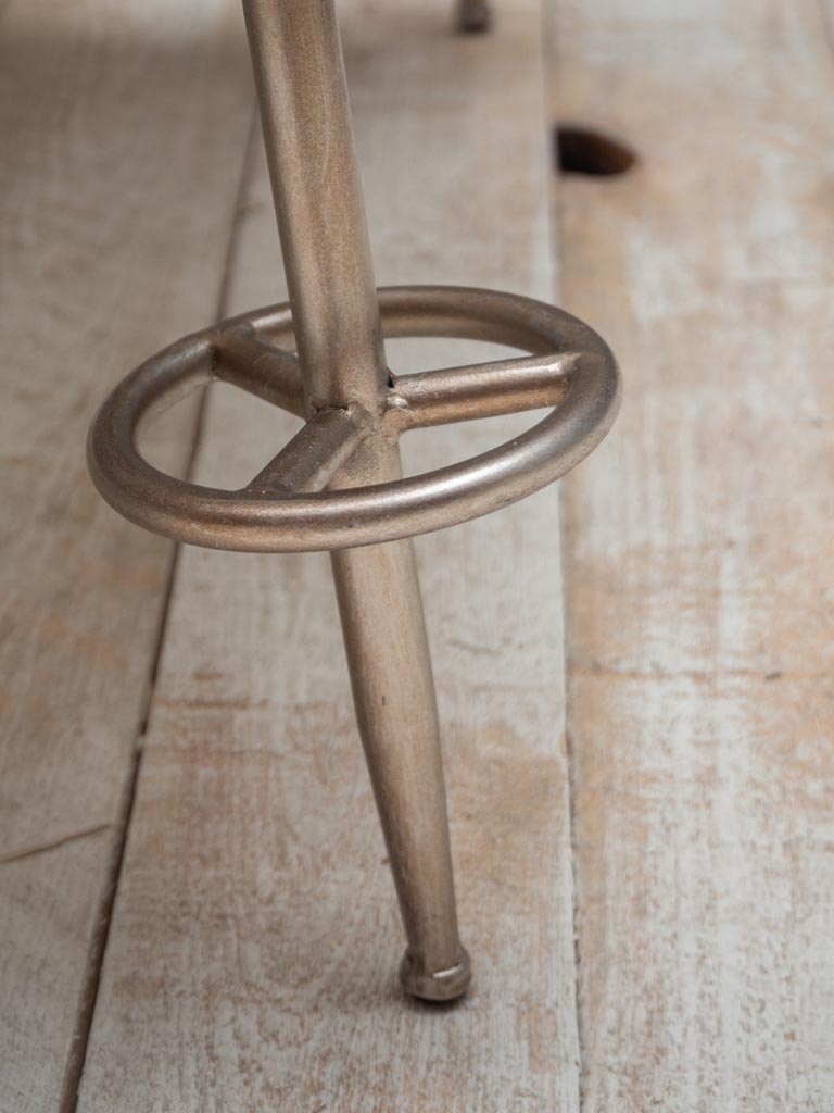 Close up view of side table legs shaped as ski poles, on wooden floor against a grey wall
