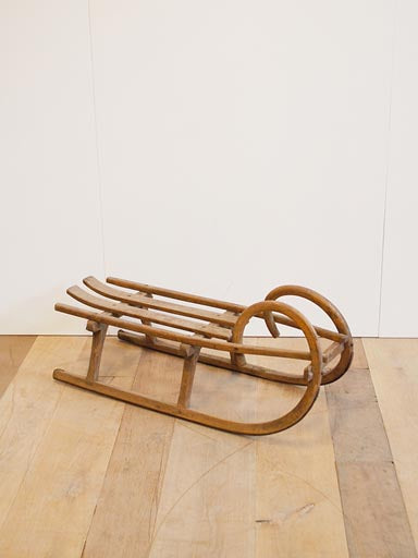 European Vintage  Wooden Sled with curved nose rails, in front of a white wall on a wooden floor